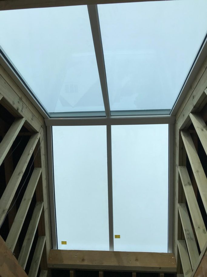 Skylight viewed from below, surrounded by wooden framing and a cloudy sky.